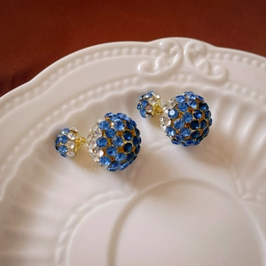Detail shot of double pearl earrings with blue and white crystals on a white porcelain dish