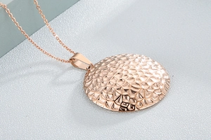 Close-up of rose gold necklace featuring a round hammered texture pendant on O-chain