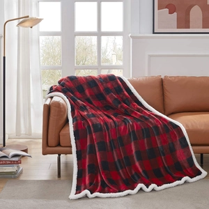 Detail of red buffalo plaid flannel blanket with white sherpa lining on a leather sofa