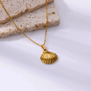 Detailed view of a gold-plated shell pendant necklace on a natural stone surface