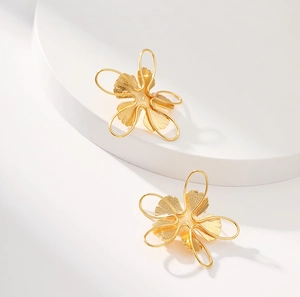 Detailed macro view of 18K gold floral earrings with elegant hollowed-out petal texture