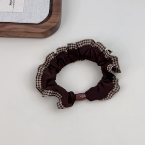 Detail of coffee brown scrunchie with plaid ruffle edge and translucent decorative bead