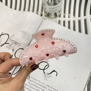 Détail de la pince à cheveux en acétate marbré rose avec cœur en strass étincelants