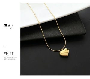 Detail of 18K gold heart pendant on a polished snake chain against a minimal background