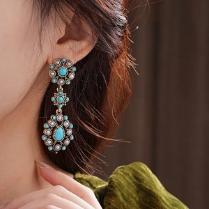 Vintage bohemian drop earrings with turquoise beads and gold floral motifs on model