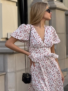 Détail de robe fleurie à col en V avec volants à la taille et manches bouffantes au soleil