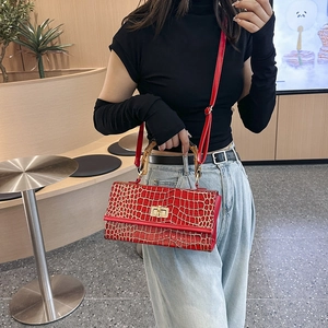 Detail of red crocodile texture handbag featuring a classic bamboo handle and metal lock