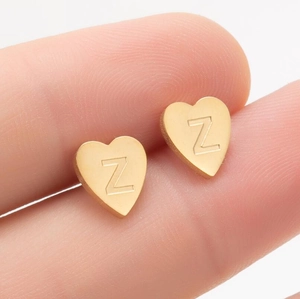 Détail d'une boucle d'oreille cœur en acier inoxydable avec la lettre Z gravée sur un doigt