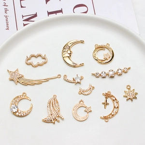 Macro shot of gold-plated celestial charms with white zircon in a white ceramic dish