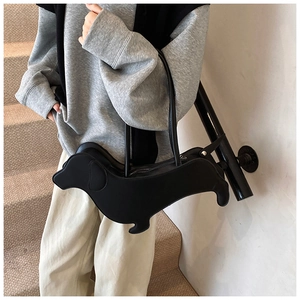 Detail of dachshund-shaped black faux leather shoulder bag with zipper and slim strap