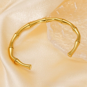 Detailed view of an 18K gold plated bamboo joint cuff bangle on champagne silk texture