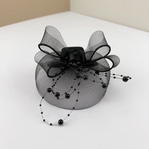 Detail of black fascinator hat featuring mesh bow, fabric rose, and dangling beads