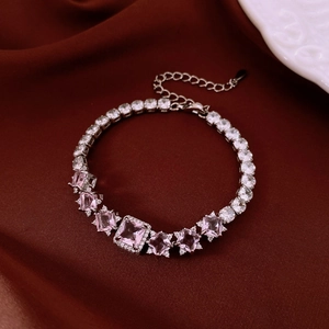 Close-up of zircon tennis bracelet with pink and clear heart stones on red silk
