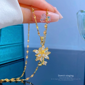 Gold titanium steel flower necklace with sparkling zircon petals on blue jewelry box