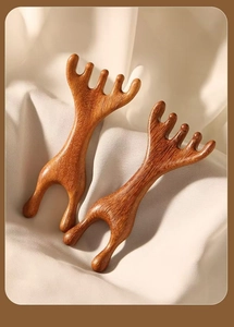 Detailed view of two natural sandalwood massage combs on a soft beige silk fabric