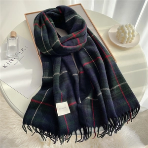 Close-up of classic navy and green plaid scarf with soft tassels and woven brand label