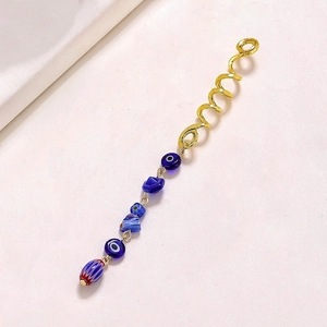 Detail of golden spiral hair ring with blue evil eye beads and natural stone pendants