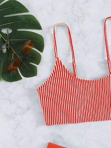 Flat lay of red and white striped bikini top with thin straps on marble background