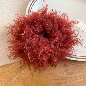 Detail of red plush hair scrunchie with fluffy texture on white ceramic plate