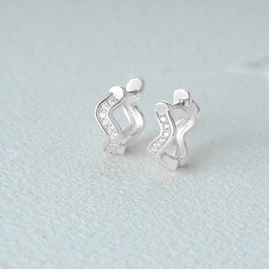 Macro shot of silver wave hoop earrings featuring S925 hallmark and sparkling cubic zirconia