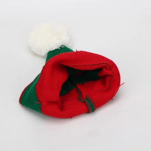 Detail showing the red and green knit texture and white pom-pom of the Christmas beanie