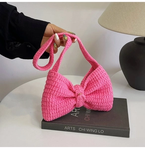 Texture détaillée du tricot d'un sac bandoulière rose vif en forme de nœud crocheté