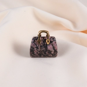 Close-up of a mini natural rose quartz handbag pendant with a golden metal handle