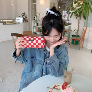 Close-up of red and white checkered canvas pouch with merciparis label on denim background