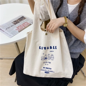 Détail du sac en toile blanc cassé avec imprimé lapin bleu et fermeture à bouton pression