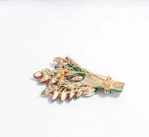 Detailed back view of golden flower brooch with secure safety pin and tiny rhinestones