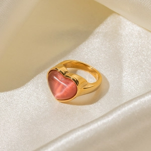 Vue macro d'une bague avec pierre oeil de chat rose en coeur sur soie beige