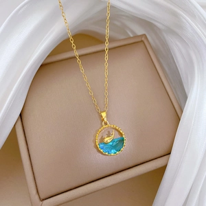 Detail of whale pendant necklace with blue crystal and gold chain on jewelry box