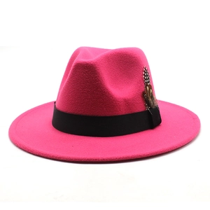 Detail of rose red fedora hat with a black ribbon band and elegant feather accent