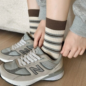 Detailed close-up of brown and beige striped cotton crew socks paired with grey sneakers