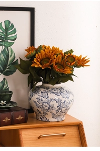 Detail einer blau-weißen Keramikvase mit Rissglasur und künstlichen Sonnenblumen