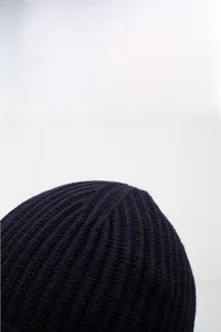 Detailed close-up of dark blue ribbed knit beanie showing thick wool texture and warmth