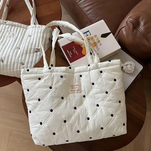 Quilted white tote bag with black polka dots and French text on wood table