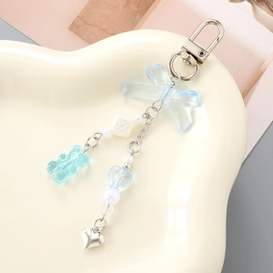 Detail of blue transparent bow and bear charm keychain on a heart-shaped tray