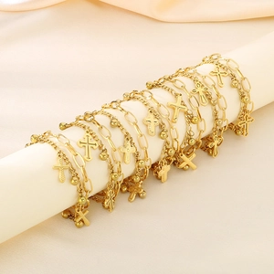 Detail of layered gold link bracelets with cross pendants on a soft fabric roll display