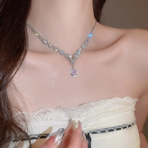 Close-up of elegant silver necklace with a pink teardrop zircon pendant on a model's neck