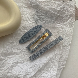 Close-up of grey marble pattern resin hair clips set with golden metal duckbill base