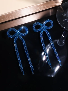 Detailed view of blue bowknot earrings with sparkling rhinestones and long tassel drop