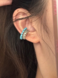 Gros plan d'un ear cuff à perles bleu ciel et d'un bijou d'oreille en métal argenté