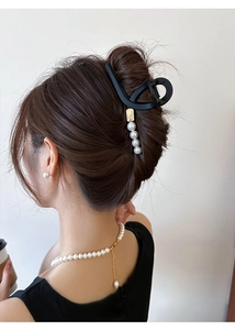 Détail d'une pince à cheveux noire mate avec perles portée sur les cheveux d'une femme