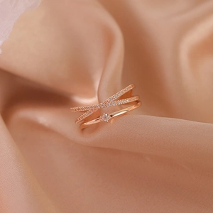Detailed macro view of rose gold double layer crisscross ring with zircons on silk