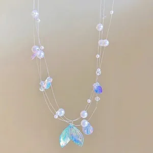 Detail of multi-layer pearl necklace featuring a shimmering fish tail pendant