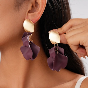 Detailed close-up of purple acrylic flower earrings with gold stud on a model