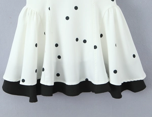 Détail de la jupe blanche à pois avec ourlet noir contrastant et plis élégants
