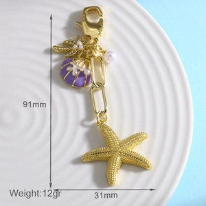 Detail view of starfish keychain with purple shell and palm tree charm on a plate