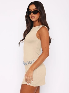 Détail de la robe moulante beige sans manches avec une ceinture chaîne en métal argenté